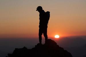 pôr do sol idílico com um montanhista no cume foto