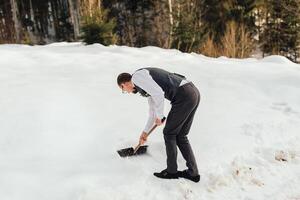 uma bonito homem pás neve dentro a montanhas, prepara trenó motivos foto