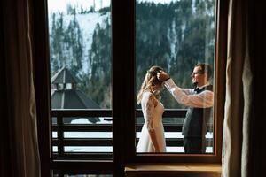 a noivo coloca uma guirlanda em a noiva contra a fundo do coberto de neve montanhas. uma Casamento casal é a comemorar uma Casamento dentro a montanhas dentro inverno. foto