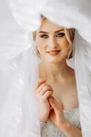 a noiva dentro uma branco vestir, véu poses dentro lindo iluminação dentro dela sala. manhã do a noiva. uma lindo tiara foto