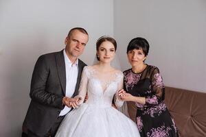 feliz pais aguarde a mãos do a noiva quem é obtendo casado e Apoio, suporte dela, vestindo uma Casamento vestir e uma grandes véu. foto