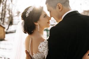 inverno casamento. uma feliz casal dentro Casamento roupas estão abraçando e sorridente dentro uma inverno parque coberto com neve em seus Casamento dia. inverno amor história do uma lindo casal dentro Nevado inverno clima foto