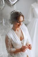 uma lindo morena noiva com uma tiara dentro dela cabelo é obtendo pronto para a Casamento dentro uma lindo roupão dentro boudoir estilo. fechar-se Casamento retrato, foto. foto