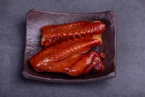 asas de frango marinadas em um prato contra um fundo escuro foto