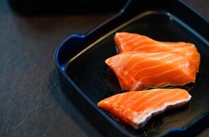 fatiado salmão em Preto prato e Preto fundo. japonês Comida foto
