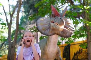 uma criança gritos às a vista do uma dinossauro. Adolescência menina dentro dinossauro. foto