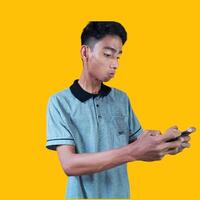 animado jovem homem segurando uma inteligente telefone vestindo uma cinzento camiseta, amarelo fundo. foto