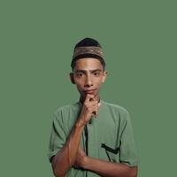 ásia homem vestindo verde muçulmano camisa em verde fundo, Perguntando para silêncio com dedo em lábios. adequado para a Ramadã tema. foto