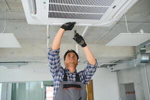 concentrado jovem indiano engenheiro configuração acima ar condicionador. foto