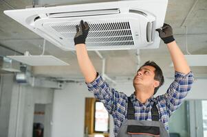 concentrado jovem indiano engenheiro configuração acima ar condicionador. foto