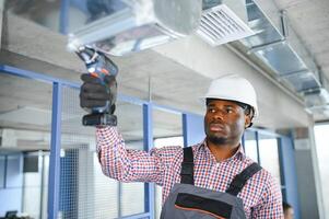 hvac africano trabalhador instalar canalizado tubo sistema para ventilação e ar condicionamento. cópia de espaço foto