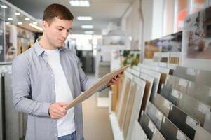 jovem homem escolhendo azulejos às construção mercado foto