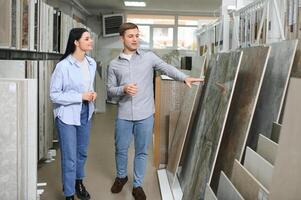 lindo jovem casal escolhendo cerâmico azulejos para seus casa conserto dentro a construção fazer compras foto