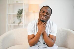 doente africano homem com dolorido garganta, retrato do eu vou Preto homem sofrimento a partir de dolorido garganta vencimento para frio, gripe, alergia foto