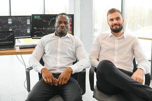 dois bem sucedido comerciante sentado dentro escritório, verificação criptomoeda em formação dados em finança mercado gráfico, apontando em monitor foto