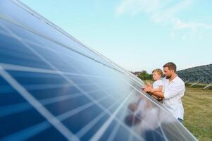 homem mostrando pequeno criança a solar painéis durante ensolarado dia. pai apresentando para dele criança moderno energia recurso. pequeno passos para alternativo energia. foto