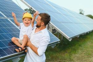 feliz pai e dele pequeno filho estão caminhando perto a solar painéis. a conceito do verde energia. foto
