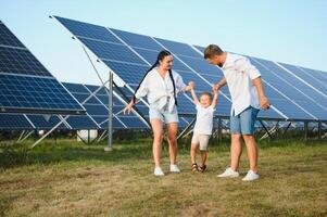 a conceito do verde energia. feliz família caminhando e tendo Diversão dentro solar painel campo. verde energia. foto