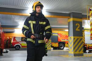 bombeiro vestindo protetora uniforme em pé dentro fogo departamento às fogo estação foto