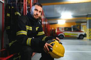 bombeiro vestindo protetora uniforme em pé dentro fogo departamento às fogo estação foto