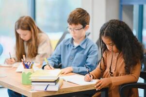 africano americano escola menina escrevendo Aprendendo sentado às escrivaninha dentro Sala de aula dentro de casa foto