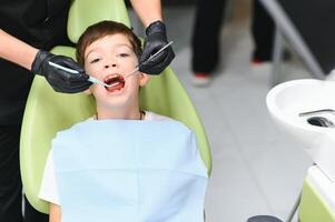 fofa Garoto sorridente enquanto dentes exame . feliz Garoto sentado dentro Dentistas cadeira e tendo Verifica acima dentes foto