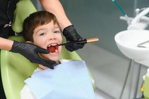 dentista examinando pequeno Rapazes dentes dentro clínica foto