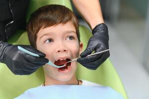 dentista examinando pequeno Rapazes dentes dentro clínica foto