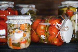 enlatado pepinos e tomates com construir tampas em uma de madeira fundo. pepinos e tomates com Lugar, colocar para texto. ações do enlatado Comida. colheita, ações para a inverno. foto