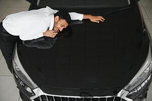 uma jovem indiano homem escolhe uma Novo carro às uma carro concessionária foto