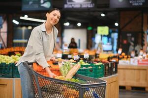 jovem mulher comprando legumes às mercearia mercado foto