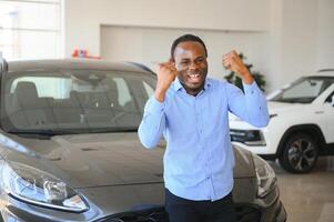 bonito homem é em pé perto dele Novo carro e sorridente foto