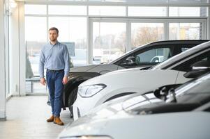 jovem homem, vendendo elétrico carros dentro a showroom. conceito do comprando ecológico carro para família foto