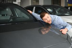 uma jovem homem escolhe uma Novo carro às uma carro concessionária. foto