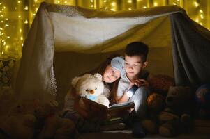 pequeno crianças lendo hora de dormir história às lar. foto