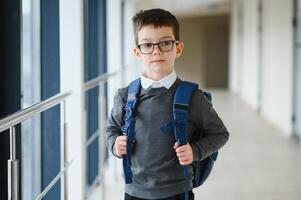 retrato do fofa escola Garoto com mochila. estudante com uma mochila às escola. costas para escola. foto