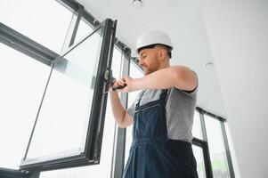 bonito jovem homem instalando baía janela dentro Novo casa construção local foto