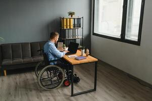 homem dentro cadeira de rodas às casa ou dentro escritório. foto