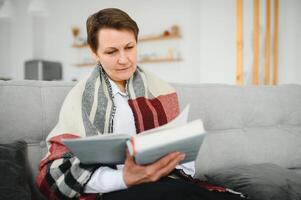 Senior mulher lendo livro às lar. foto