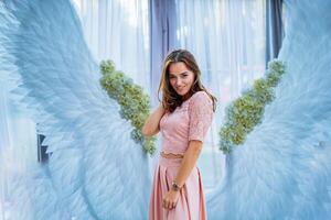 uma mulher em pé dentro frente do a anjo asas pano de fundo foto