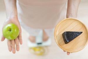 mulheres de corpo magro escolhem durante alimentos saudáveis e junk food, mulheres escolhem maçã verde para dieta. boa comida saudável. perda de peso, equilíbrio, controle, redução de gordura, baixas calorias, rotinas, exercícios. foto