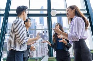 equipe de jovem empresário asiático tem uma pequena reunião de equipe para o próximo projeto de marketing e gerenciamento de vendas com vista de arranha-céu para inicialização de negócios e conceito de educação foto