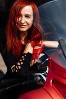 ruivo mulher posando em uma motocicleta. uma mulher com vermelho cabelo sentado em uma motocicleta foto