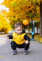 jovem Garoto dentro amarelo Jaqueta jogando com bola. uma alegre jovem Garoto vestindo uma amarelo Jaqueta alegremente tocam com dele bola. foto