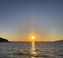 pôr do sol sobre a mar com uma barco dentro a distância foto