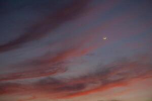 crescente lua às hipnotizante pôr do sol céu. foto