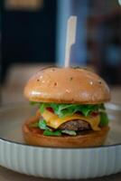 delicioso Hamburguer de queijo com carne de porco e vegetal dentro pão foto