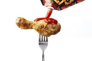 frango perna com ketchup em uma garfo isolado em branco foto