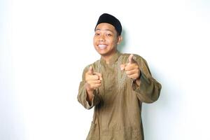 sorridente ásia muçulmano homem vestindo Koko roupas apontando às Câmera com excitação isolado em branco fundo foto