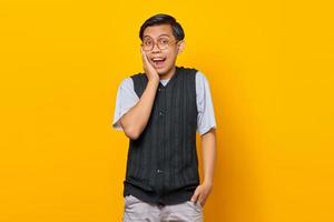 retrato de jovem asiático surpreso olhando para a câmera isolada em fundo amarelo foto